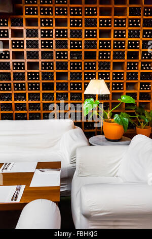 Sofas und Blumenvase in der Nähe von Weinregale in einem Restaurant. Stockfoto