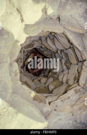 Wadi Bani Kharus, Oman.  Junger Mann in eine unterirdische Wasserkanal (Falaj) arbeiten, entfernen von Schmutz und Salzablagerungen. Stockfoto