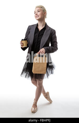 Studioaufnahme von einer Ballerina Modell ein Take-away Cup in ihrer rechten Hand und ein Paperbag in ihrer linken Hand hält. Stockfoto