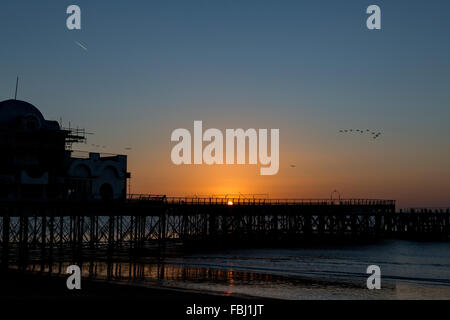 Sonnenaufgang hinter South Parade Pier in Southsea. Kalten knackig morgen was in einem Ausbruch von Farbe im Meer spiegelt. Stockfoto