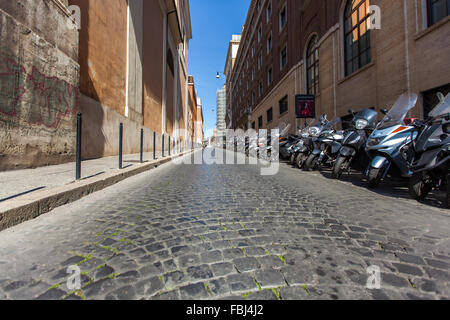 Tourismus und Sehenswürdigkeiten, schmale leere Straße in Rom am Nachmittag. Geparkte Fahrräder und Motorroller am Straßenrand Stockfoto