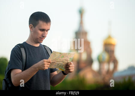 Porträt des jungen hübschen Reisenden Mann mit Rucksack tragen legere Kleidung mit Blick auf die Karte vor Kirche des Erlösers auf Spi Stockfoto