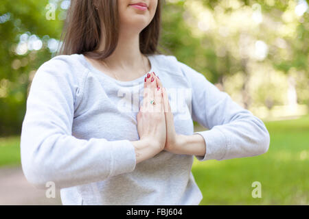 Schöne junge Frau Handflächen berühren Namaste-Geste, Hände mit rot gelackte Nägel Maniküre und Goldring mit Nahaufnahme Stockfoto