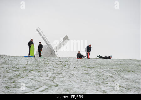 Die Menschen genießen Reiten Schlitten hinunter einen verschneiten Hang an einem Wintertag in Clayton in East Sussex, UK. Stockfoto