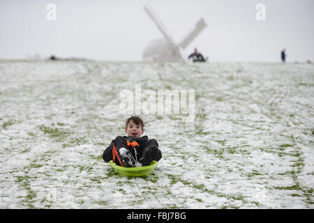 Ein Junge Folien unten einen verschneiten Hang auf einem Schlitten in Clayton, East Sussex, UK. Stockfoto