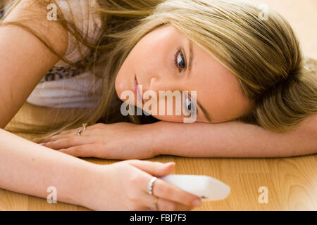 Schöne junge Frau, 16 Jahre alt, Kopf und Schultern, blond, blaue Augen, mit traurigen Ausdruck, Telefon, während am Boden. Soft Focus Stockfoto