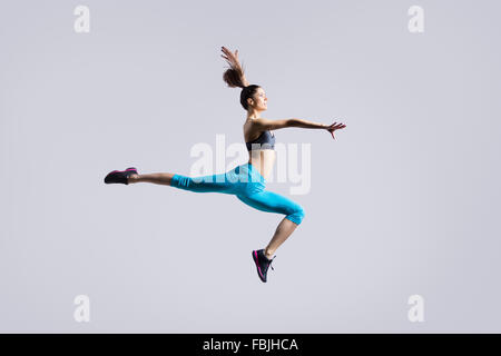 Eine attraktive wunderschöne junge passen moderne Frau in blauen Sportbekleidung mit Pferdeschwanz Aufwärmen trainieren, tanzen, springen Stockfoto