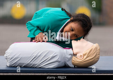 Eine Schulmädchen lernt lebensrettende erste-Hilfe-Techniken durch das üben an einem Dummy in der Schule. Stockfoto