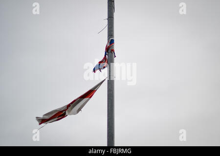 Eine zerrissene und zerfetzten Union Jack und Nordirland Fahnen Fliege aus Belfast Laternenpfahl Stockfoto