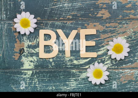 Wort-Bye mit Holzbuchstaben auf rustikale Oberfläche und weiße Gänseblümchen geschrieben Stockfoto