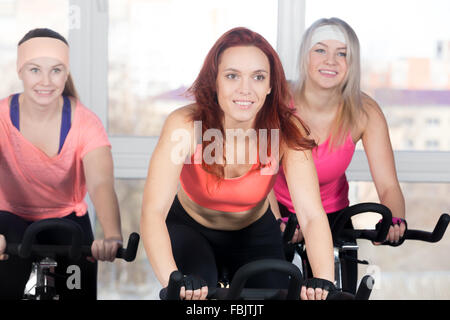 Fitness-Praxis, Gruppe von drei Fit schöne fröhliche Frauen im Sportclub, Radfahren tun Cardio-Übungen für abnehmen Stockfoto