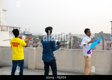 DHAKA, Bangladesch 14. Januar 2016: Menschen von alten Dhaka Drachen auf dem Dach ihres Gebäudes anlässlich des Shakrain Festivals in Dhaka am 14. Januar 2016. Das Shakrain Festival hat in Shakhari Bazar Gegend in der Altstadt von Dhaka stattgefunden. Shakrain Festival auch bekannt als Kite Festival wird am Ende des Monats Poush Bangla in Dhaka, Bangladesch gefeiert. Shakrain Festival in einem alten, berühmten und wichtigen jährlichen Festival von Bangladesch. Es ist das Symbol der Einheit und Freundschaft in Bangladesch. Shakrain Festival ist wichtig vor allem für viele bunte Drachen fliegen, Stockfoto