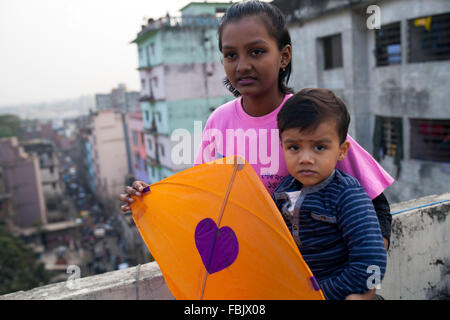 DHAKA, Bangladesch 14. Januar 2016: Menschen von alten Dhaka Drachen auf dem Dach ihres Gebäudes anlässlich des Shakrain Festivals in Dhaka am 14. Januar 2016. Das Shakrain Festival hat in Shakhari Bazar Gegend in der Altstadt von Dhaka stattgefunden. Shakrain Festival auch bekannt als Kite Festival wird am Ende des Monats Poush Bangla in Dhaka, Bangladesch gefeiert. Shakrain Festival in einem alten, berühmten und wichtigen jährlichen Festival von Bangladesch. Es ist das Symbol der Einheit und Freundschaft in Bangladesch. Shakrain Festival ist wichtig vor allem für viele bunte Drachen fliegen, Stockfoto