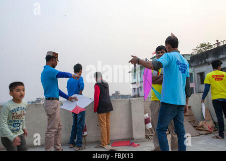 DHAKA, Bangladesch 14. Januar 2016: Menschen von alten Dhaka Drachen auf dem Dach ihres Gebäudes anlässlich des Shakrain Festivals in Dhaka am 14. Januar 2016. Das Shakrain Festival hat in Shakhari Bazar Gegend in der Altstadt von Dhaka stattgefunden. Shakrain Festival auch bekannt als Kite Festival wird am Ende des Monats Poush Bangla in Dhaka, Bangladesch gefeiert. Shakrain Festival in einem alten, berühmten und wichtigen jährlichen Festival von Bangladesch. Es ist das Symbol der Einheit und Freundschaft in Bangladesch. Shakrain Festival ist wichtig vor allem für viele bunte Drachen fliegen, Stockfoto