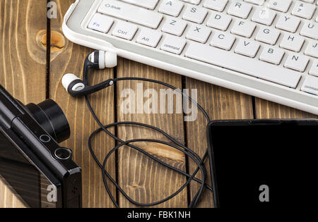 Laptop, Smartphone, Foto-Kamera und Kopfhörer auf hölzernen Hintergrund Stockfoto