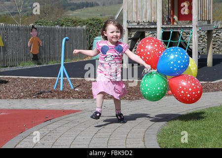 Kleine Mädchen spielen und laufen mit Luftballons in einer Gärtnerei, Spaß Stockfoto