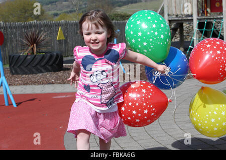 Kleine Mädchen spielen und laufen mit Luftballons in einer Gärtnerei, Spaß Stockfoto