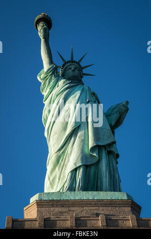 Blick auf die ganze Statue of Liberty von unten mit einem wolkenlosen blauen Himmel. Stockfoto