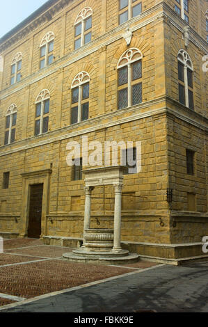 Palazzo Piccolomini und Pozzo dei Cani gut mit frühen Morgennebel in Piazza Pio II, Pienza, Toskana, Italien Stockfoto