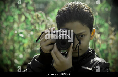 Ein kaukasischer boy Holding eine Kamera in den dichten Dschungel, die versuchen, eine Aufnahme zu machen. Stockfoto