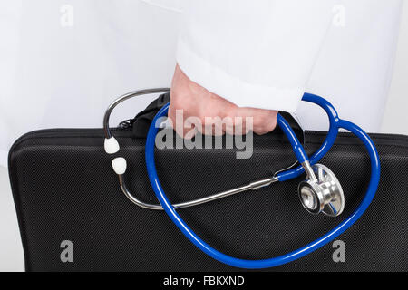 Arzt in weiße Tunika mit schwarzen Aktenkoffer und Stethoskop in der Hand. Er geht auf einen Besuch seiner Patienten. Stockfoto