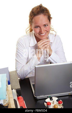 Business-Frau am Laptop hinter ihrem Schreibtisch sitzt lächelnd Stockfoto