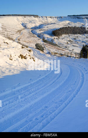 Ein Feldweg führt durch eine verschneite und hügelige Landschaft im Norden Englands. Blick nach Coombes Rand nahe Glossop, Derbyshire. Stockfoto