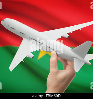 Flugzeug in der Hand mit Nationalflagge auf Hintergrund-Serie - Burkina Faso Stockfoto