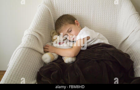 Jungen schlafen mit Teddybär Stockfoto