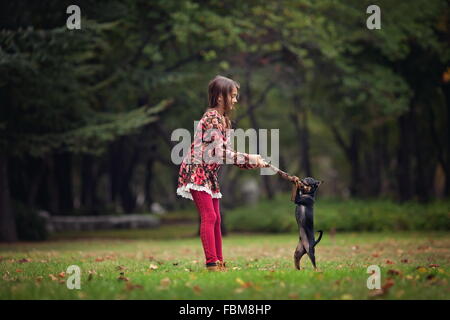 Mädchen spielen mit ihrem Welpen Hund im park Stockfoto