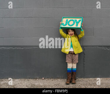 Glückliches Mädchen mit einem Freude-Schild Stockfoto