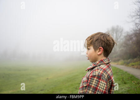 Seitenansicht eines jungen steht in einem Park am nebligen Tag Stockfoto