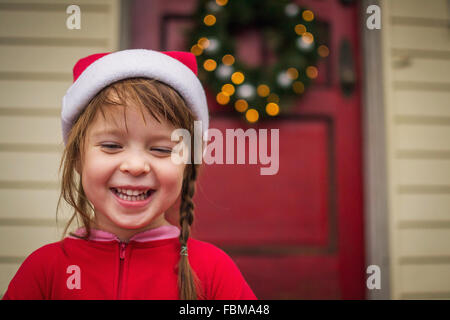 Glückliches Mädchen im Weihnachten Hut stehen vor Haus Stockfoto