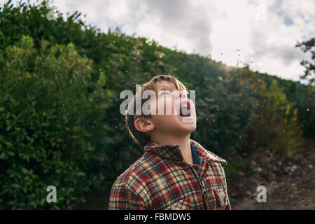 Junge versucht, Regentropfen in den Mund zu fangen Stockfoto