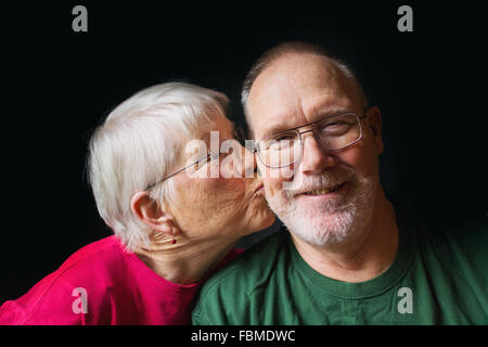 Ältere Frau küssen Wange des älteren Menschen Stockfoto