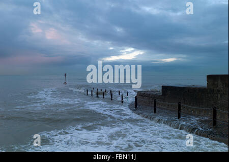 Wellen brechen über Buhne, Dämmerung Himmel, Hove, UK Stockfoto