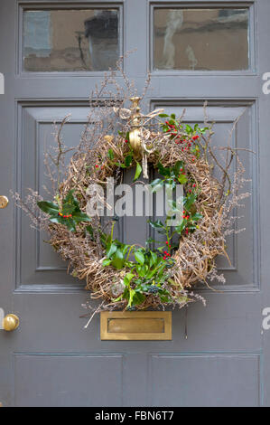 Weihnachtskranz an der Haustür aufhängen Stockfoto