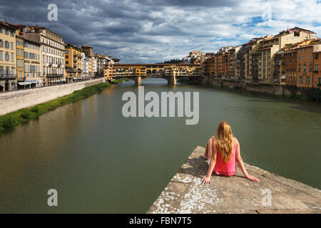 Eine junge Frau, genießen den Blick auf die Ponte Vecchio und den Fluss Arno, Florenz, Toskana, Italien. Stockfoto