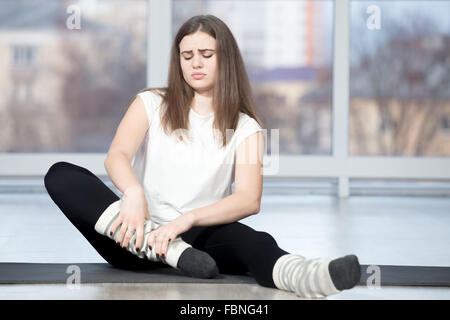 Porträt des verletzten unglücklich Fit junge schöne Frau im Sportverein, berühren den Knöchel nach dem Training in der Klasse sitzen Stockfoto