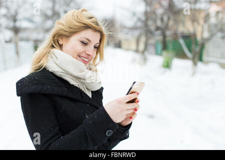 Lässige Frau Tippen auf den Smartphone-Winter außerhalb Stockfoto