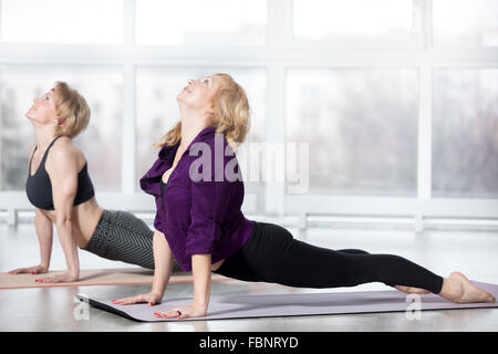 Fitness, stretching Praxis, Gruppe von zwei attraktiven Lächeln passen Reife Frauen Sportswear Training im Sportverein Stockfoto