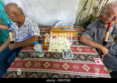 Alte Männer sitzen vor einem Café Okey Spiel und Wasser Türkei Shisha rauchen Pfeife im alten Pergamon Basar, Bergama Rauchen Stockfoto