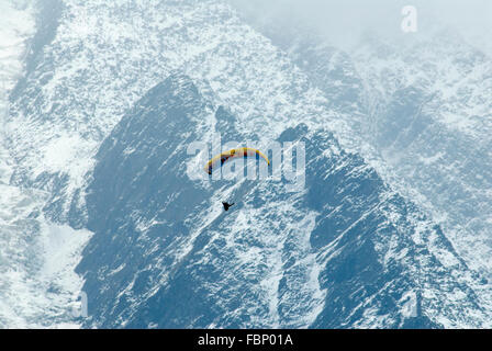 Gleitschirmflieger schweben hoch über dem Tal von Chamonix mit Schnee bestäubt Flanken des Mt-Blanc-Massiv hinter Stockfoto