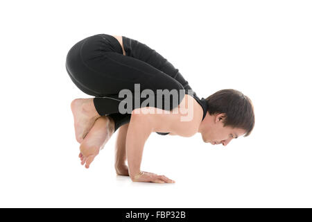 Sportlicher junger Mann arbeiten heraus, Handstand Yoga Asana, Kran (Krähe)-Pose mit gekreuzten Beinen, Bakasana für Schultern Stockfoto