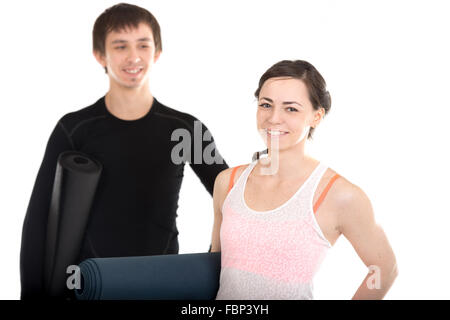 Porträt von glücklich lächelnden jungen Mann und Frau mit gefalteten Yoga Pilates Matten, sportliches Paar vor dem Training Stockfoto
