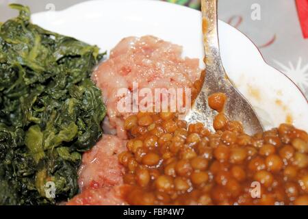 Schüssel mit gekochtem Spinat, gekocht, Salami und Linsen Stockfoto