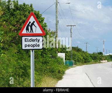 Schild warnt über ältere Menschen überqueren einer Straße Stockfoto