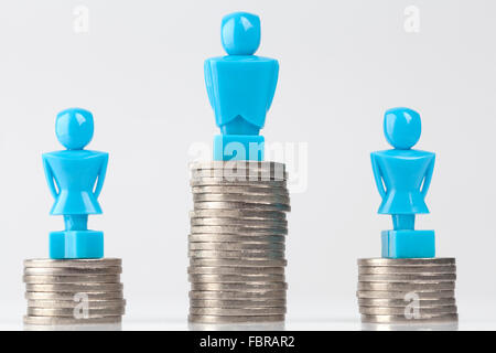 Ein Rüde und zwei weibliche Figuren stehen auf Pfählen von Münzen. Held aussehen. Einkommens-Ungleichheit-Konzept. Stockfoto