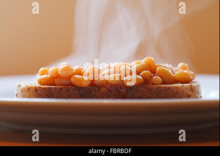 Gebackene Bohnen auf Toast mit Dampf steigt. Stockfoto