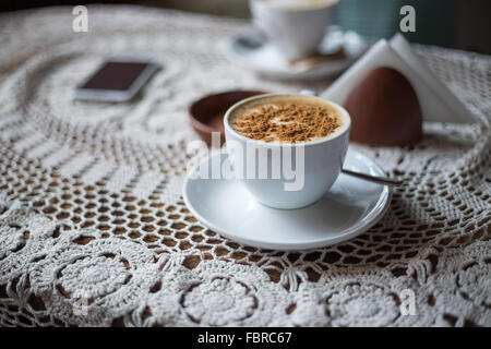 Tasse Cappuccino mit gemahlenem Zimt auf dem Tisch im café Stockfoto